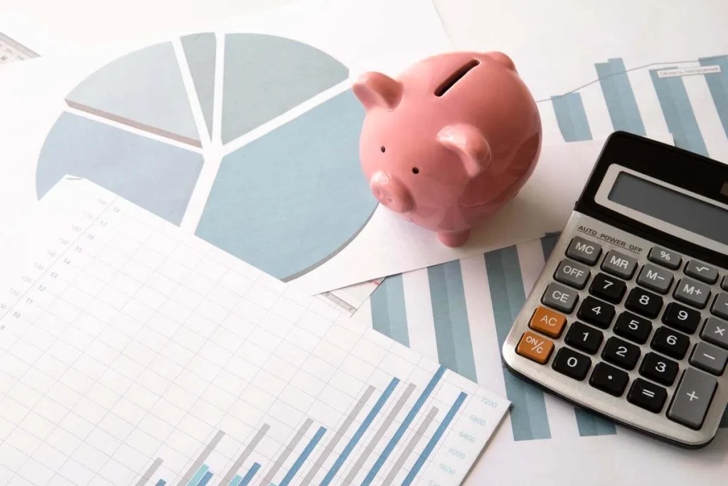 graphique, calculatrice et tirelire rose représentant les coûts financiers